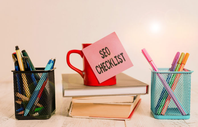 Word writing text Seo Checklist. Business concept for list of items required to optimize the search engine Coffee cup blank sticky note stacked books pen metal holders wooden table.